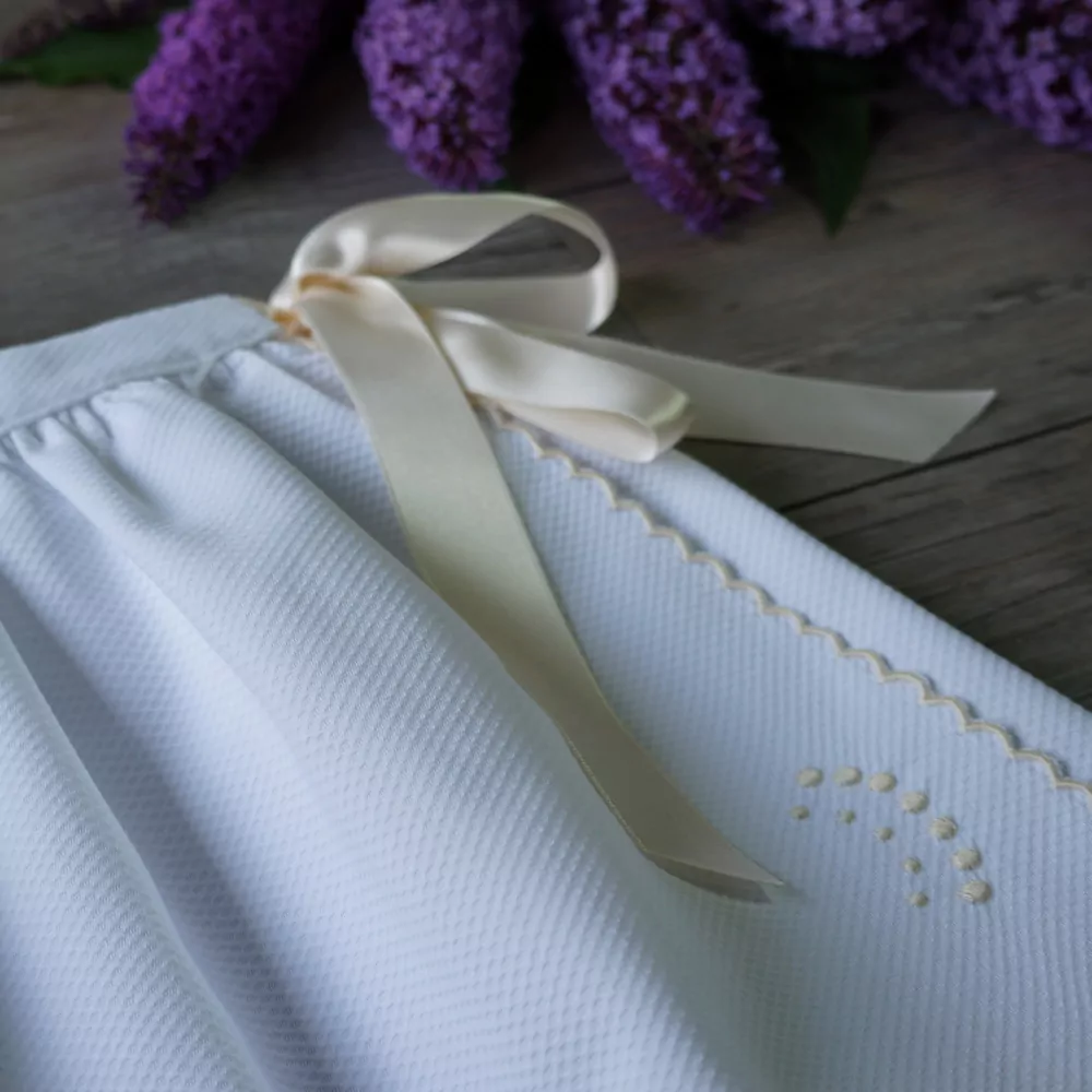 Detalle faldón festoneado blanco y beige