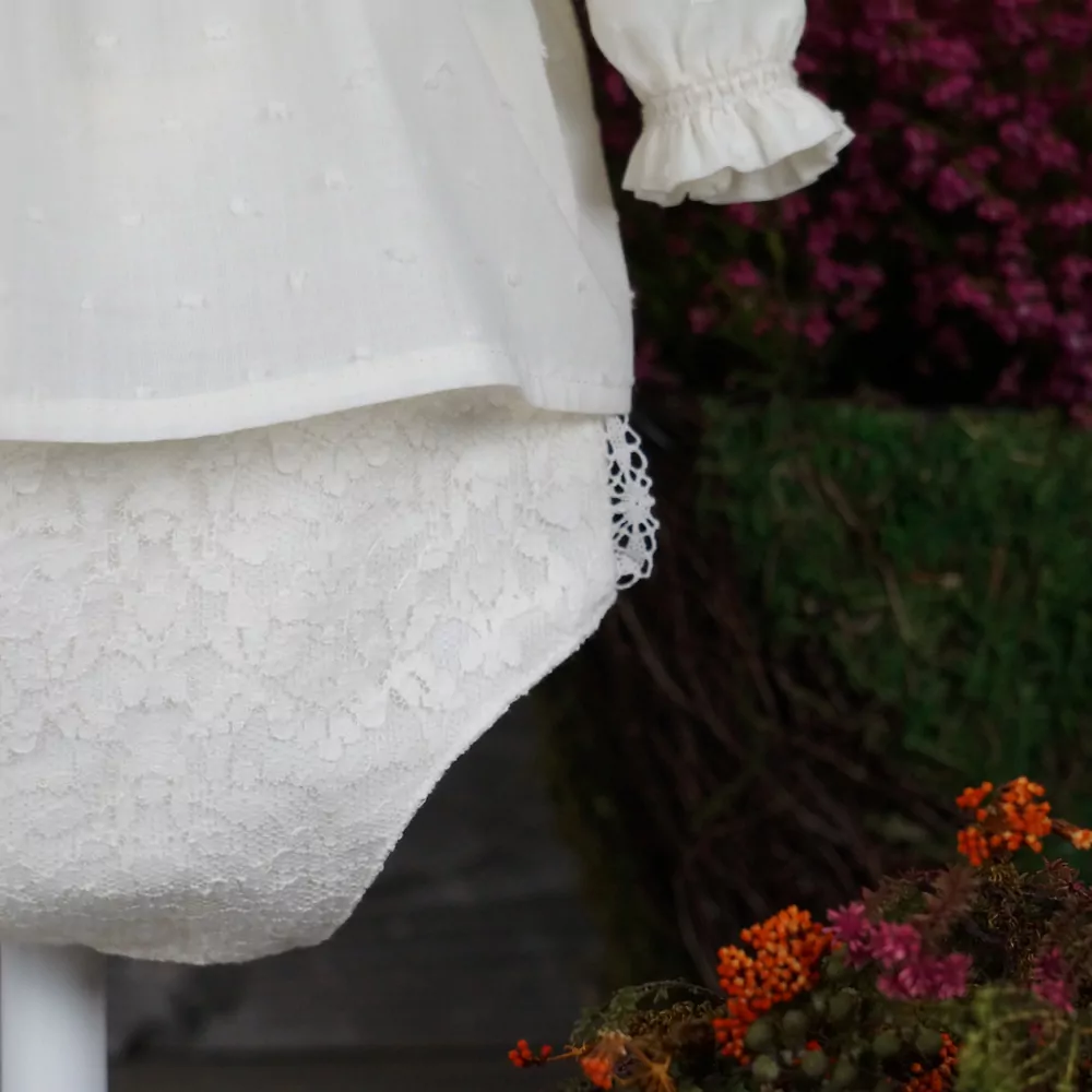 Detalle conjunto blusa y cubrepañal marfil